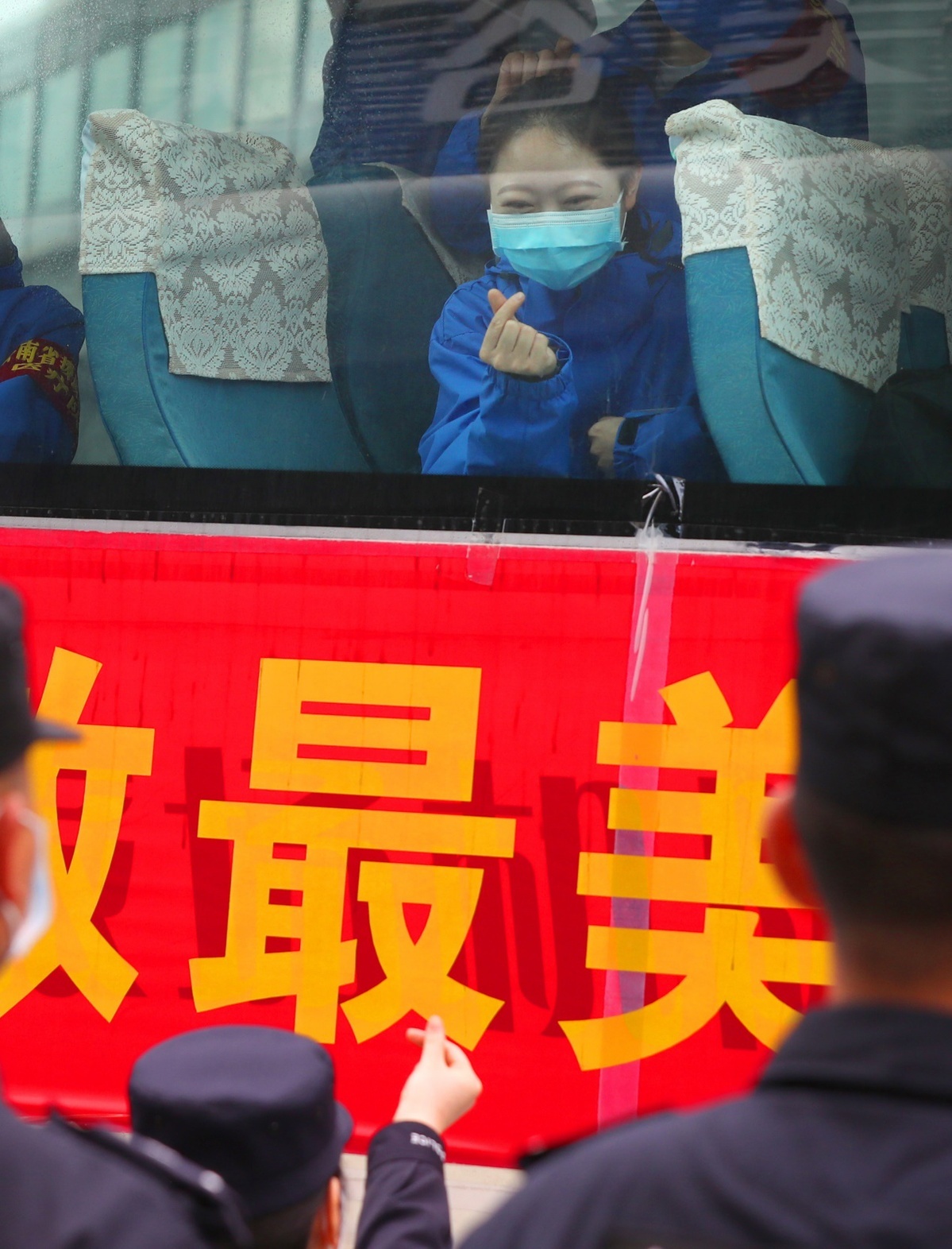 3月22日,云南省医疗队队员与警察做比心手势告别.