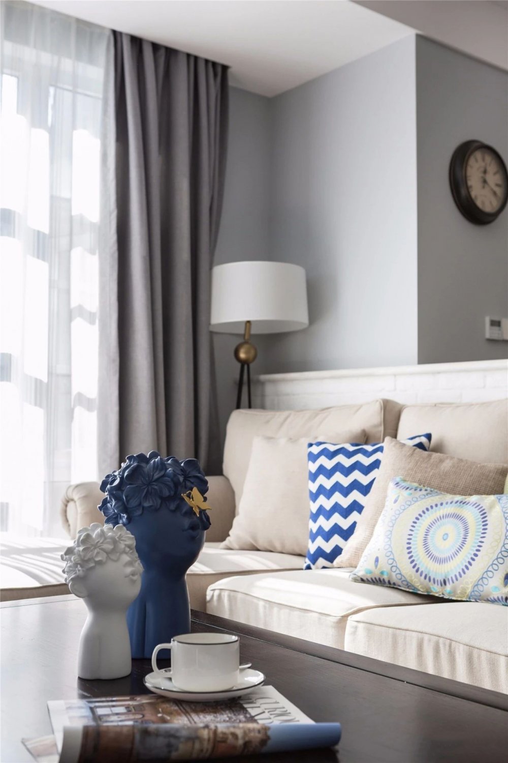 米色沙发搭配灰色窗帘,蓝白抱枕与艺术摆件,增添空间活力