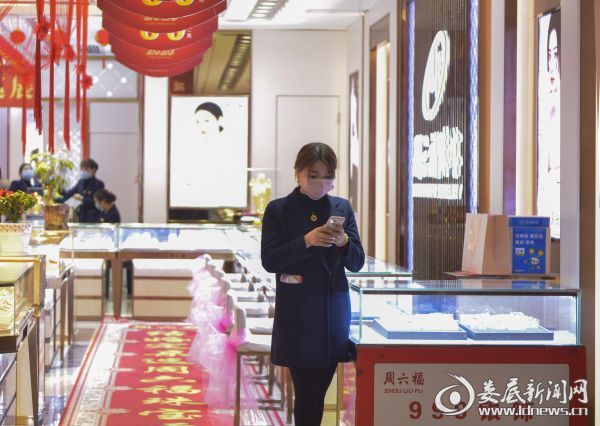 (由于没有顾客,一名珠宝店销售人员在门口玩起了手机)