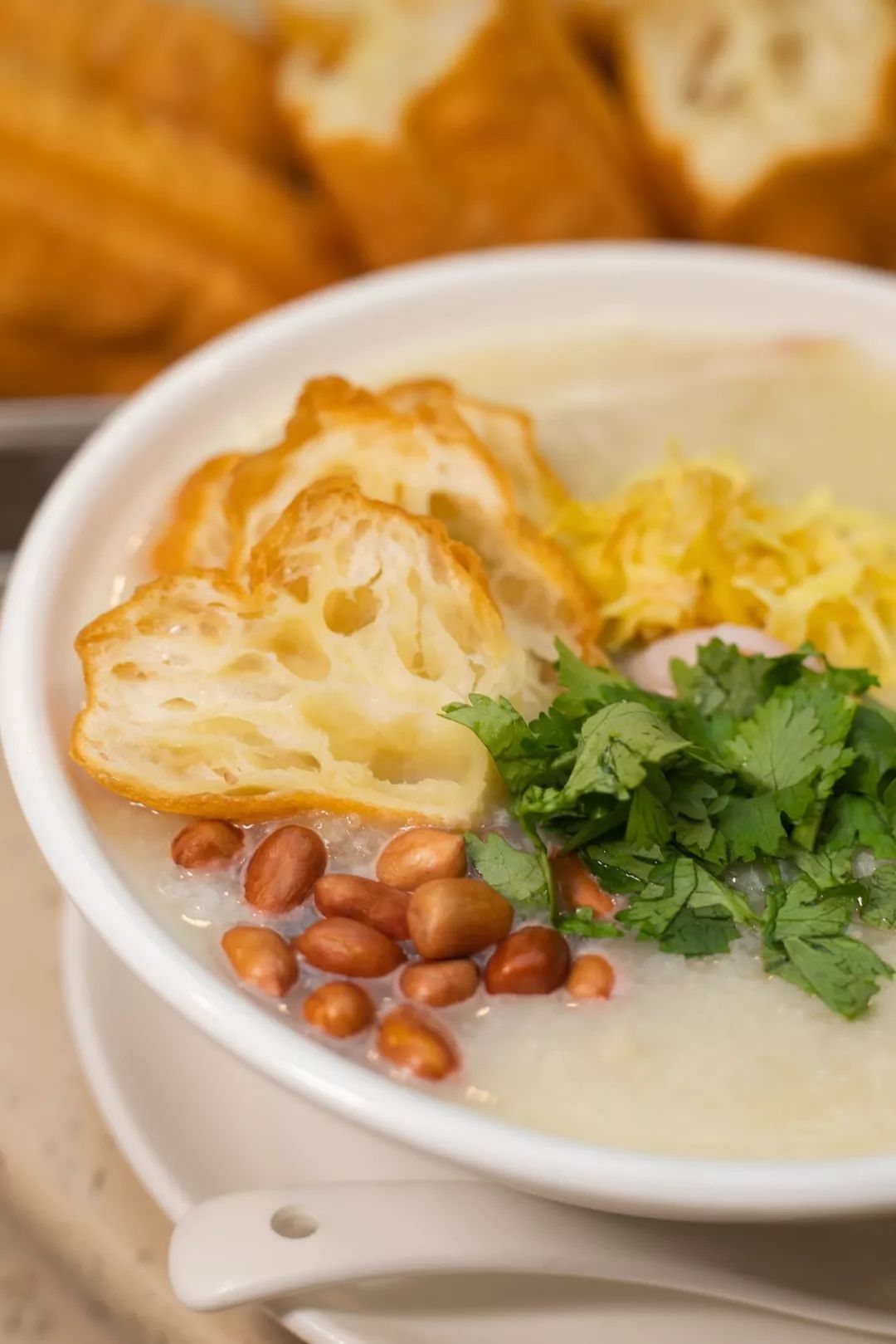 而后滚粥冲入,碗内的食材被一烫即熟,最后撒入一捧香脆的炸花生和油条