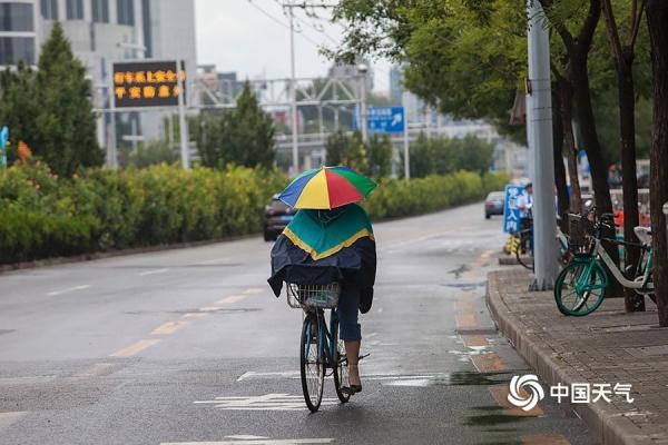光明网：雨水添凉意 北京街头行人短袖换长衫