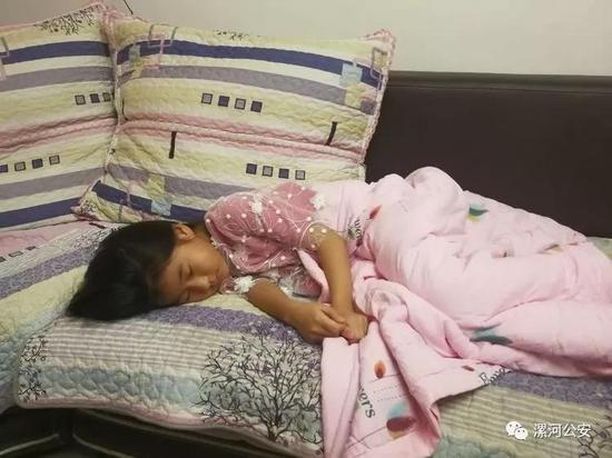 八岁的女儿果果蜷缩在沙发上已经睡着,桌上是用碗扣着的饭菜,桌边还