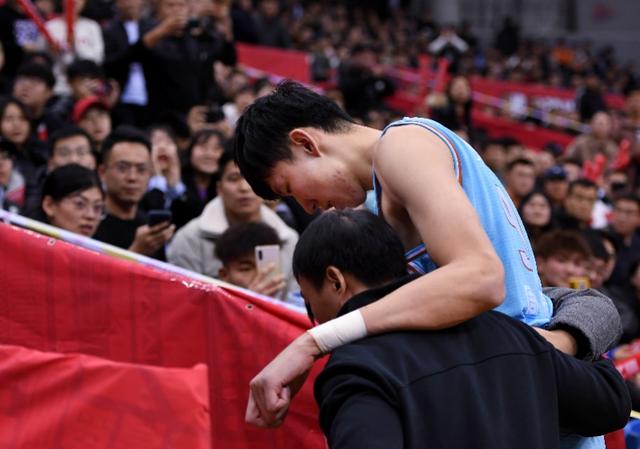 2019年12月29日,受伤的周琦(上)在工作人员搀扶下离场.新华社发