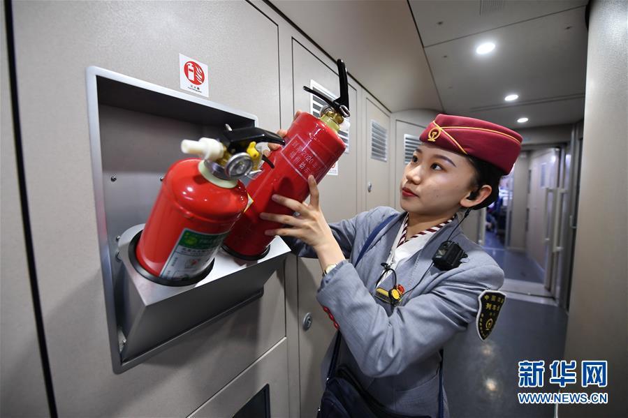 1月14日,南昌铁路局福州客运段列车长樊思萱在动车上检查灭火器.