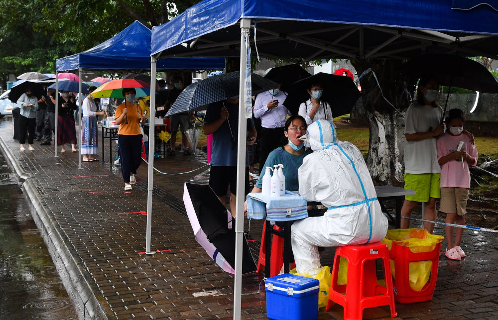 8月10日，海口市民和游客在风雨中排队做核酸。新华社记者 杨冠宇 摄