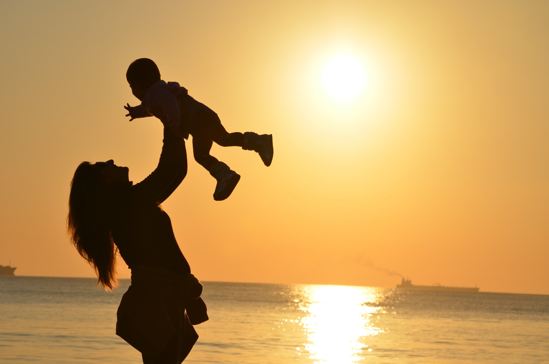 woman-carrying-baby-at-beach-during-sunset-51953.jpg