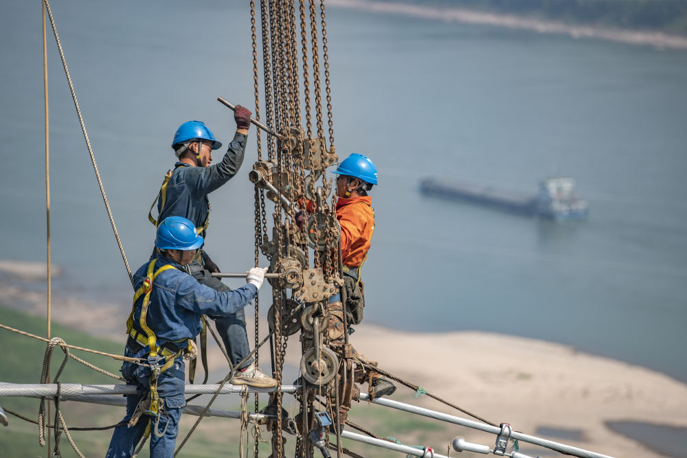 ↑9月13日，工人在白鹤滩-浙江±800千伏特高压直流输电线路工程(重庆段)江津长江大跨越施工现场作业。