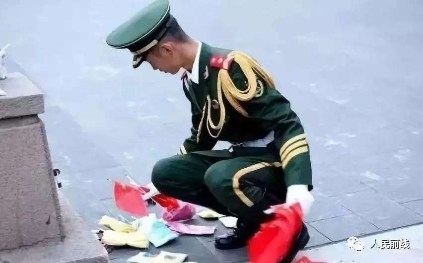 一名战士蹲下捡起了散落在地的国旗.