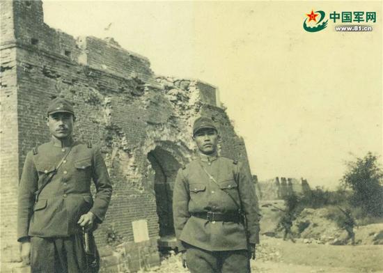 德田(左)在遭日军炮击后残破的宛平城东门(顺治门)前留影。