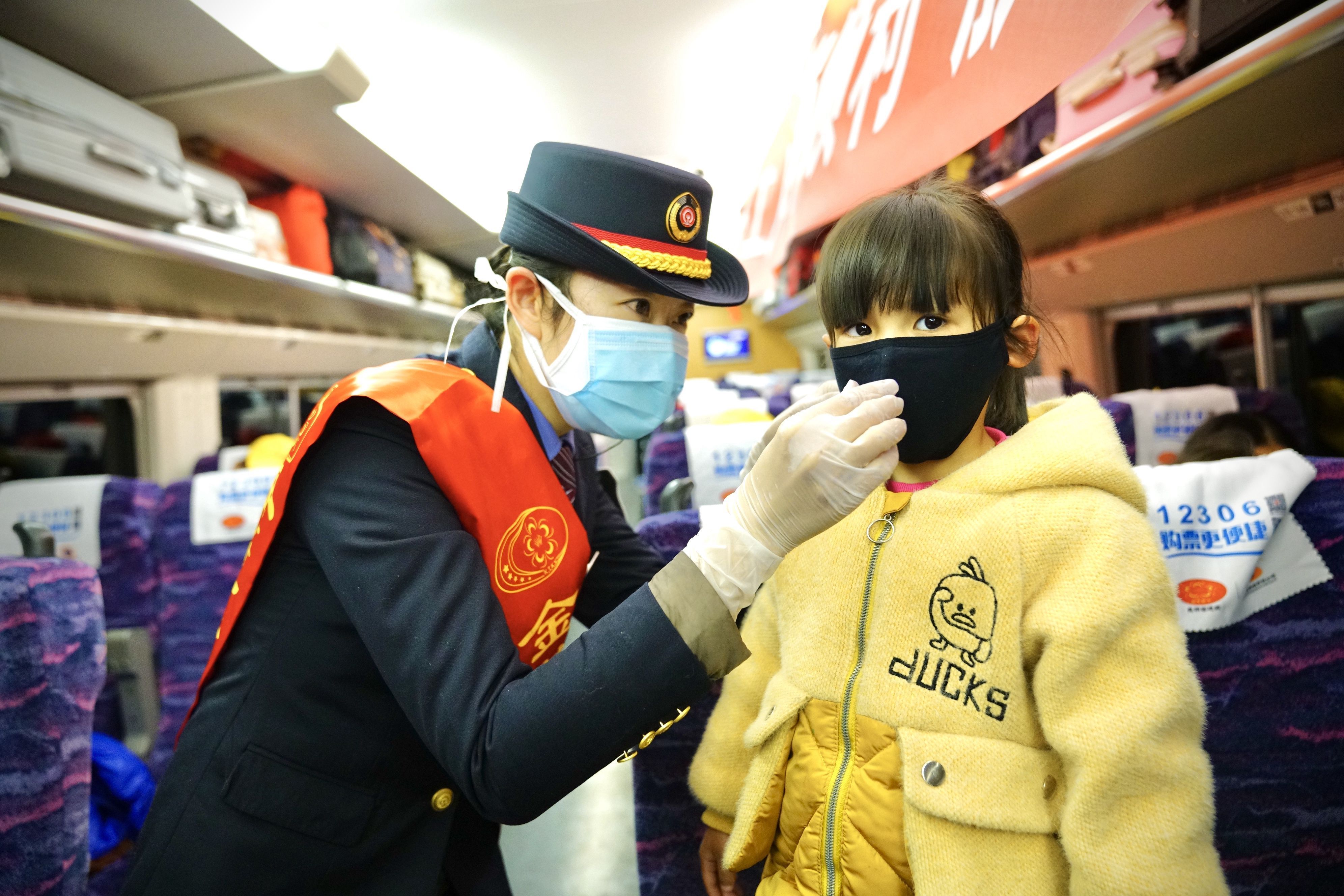 113 列车长为务工人员随行的小朋友戴口罩，并向未佩戴口罩的旅客发放一次性口罩。（李苑摄）_副本.jpg
