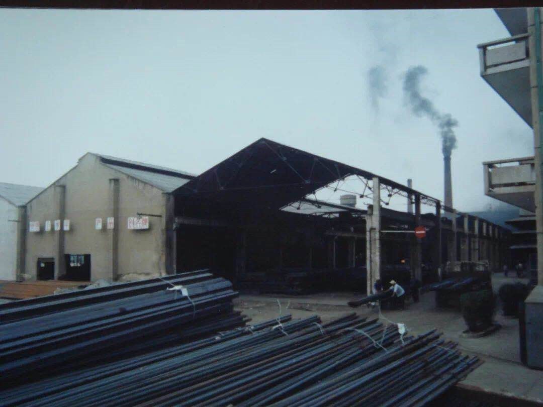 图为沙钢建厂初期的轧钢车间，笔直的烟囱中正冒着滚滚浓烟。图片来源：中国冶金报社官方微信.jpg?x-oss-process=style/w10