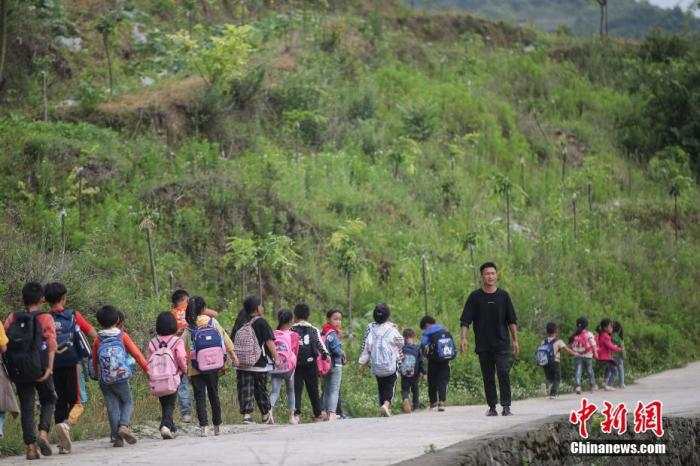 资料图：一名“90后”乡村教师组织学生排队上下学。