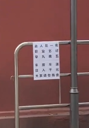 职业乞讨者旁边的警示语（视频截图）