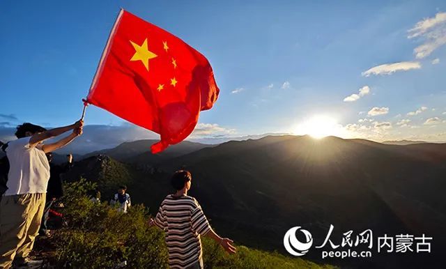 学生挥舞着国旗迎接清晨的第一缕阳光。人民网记者 张雪冬摄