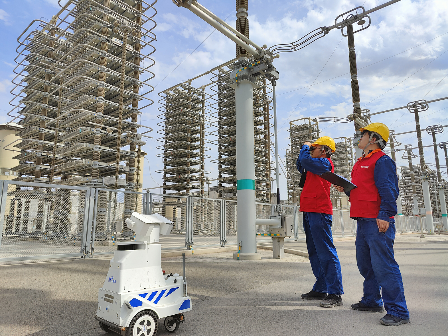 6月13日，在准东—皖南±1100千伏特高压直流输电工程昌吉换流站，工人正和巡检机器人一起对换流站运维情况进行巡视.jpeg