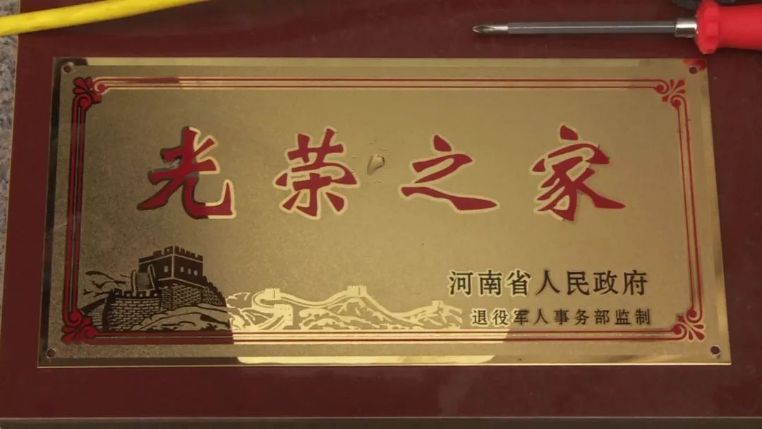 辖区工作人员正在为烈属,军属和退役军人家庭悬挂"光荣之家"牌匾