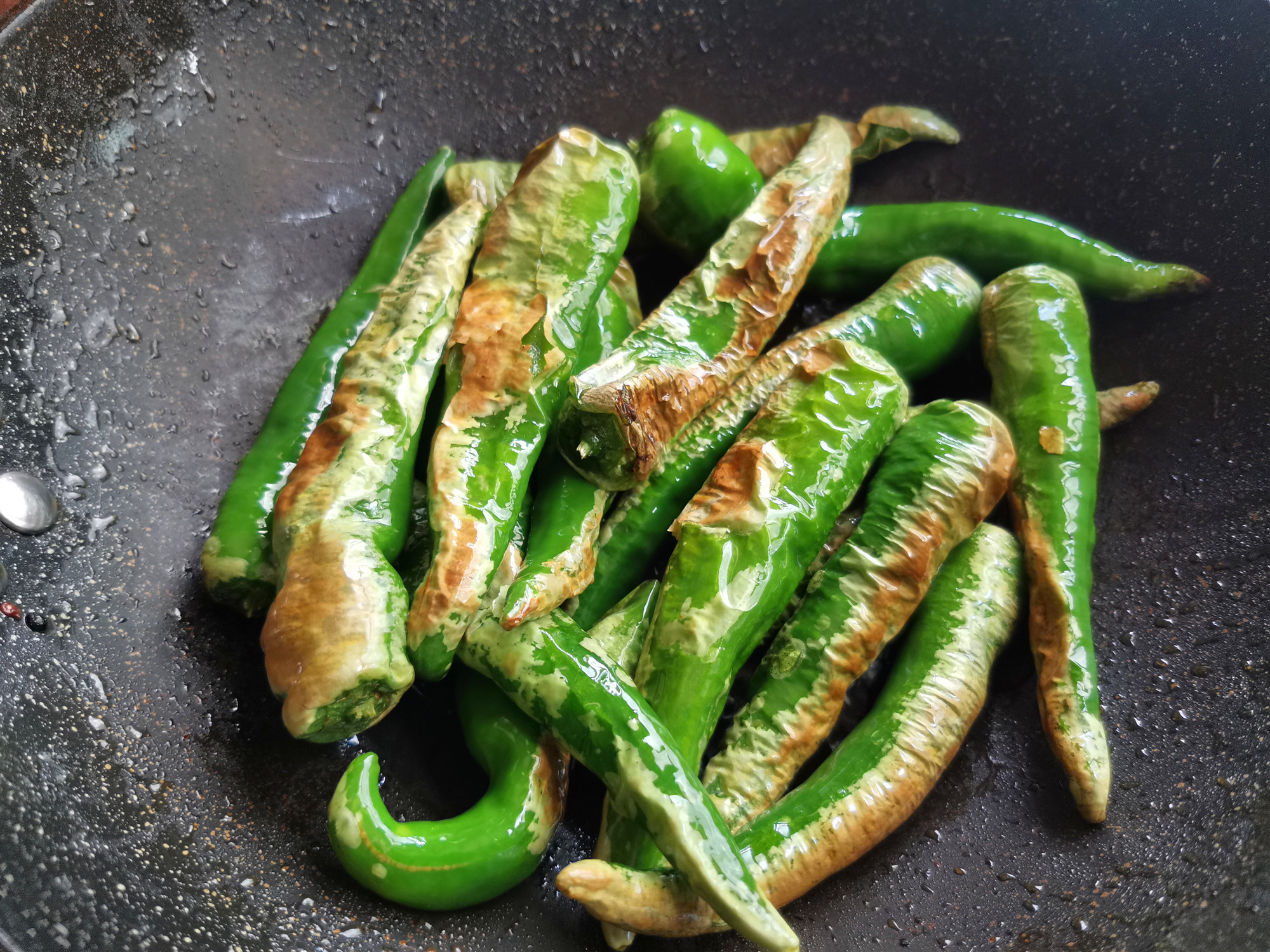 3.锅加油烧热,下入尖椒煎制,将辣椒两面煎至表面起皱皮4.