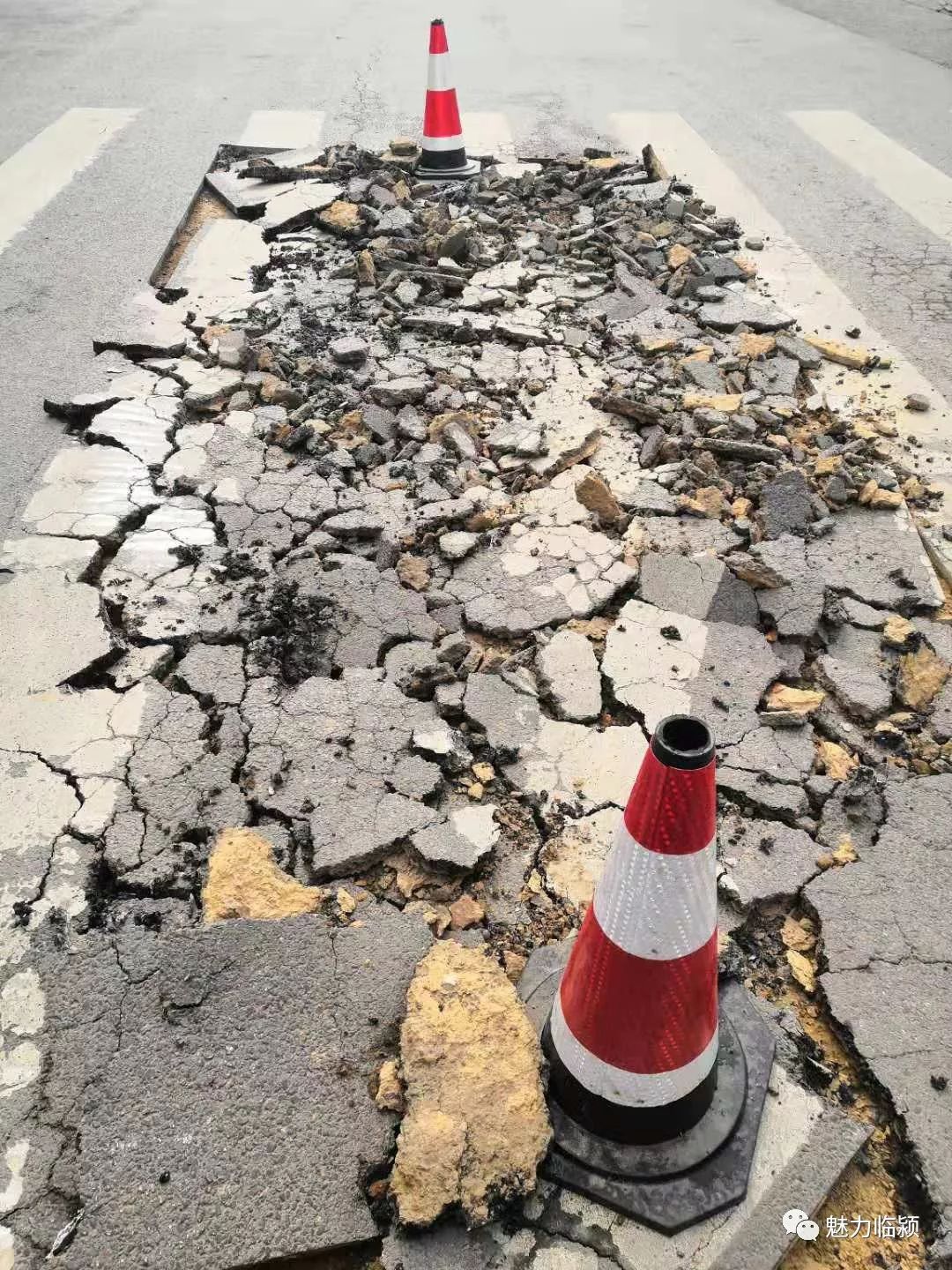 破损的路面已经被切割等候修补,反光锥已经摆放.
