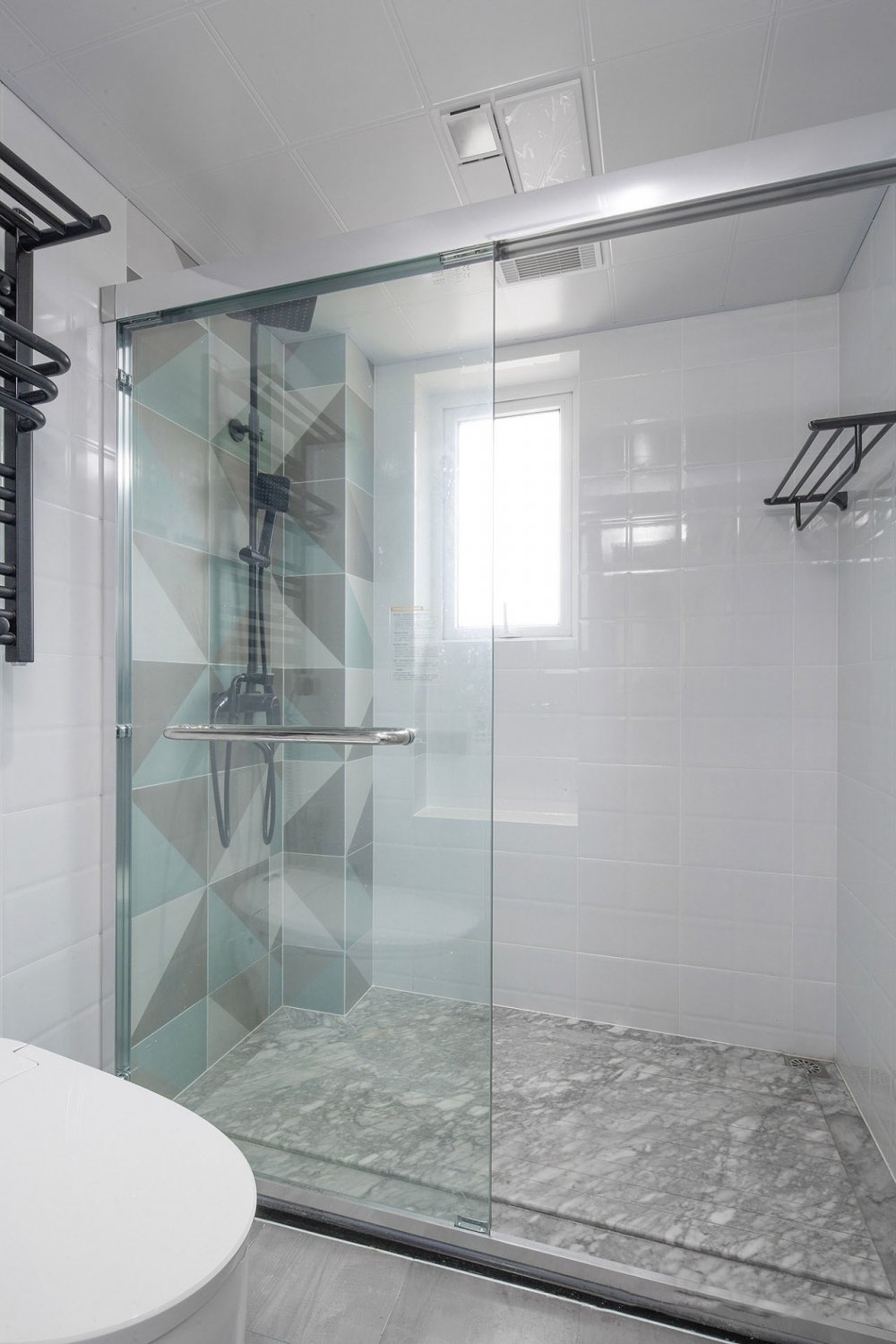 卫生间淋浴区地面采用大理石拉槽防滑,并留出导流槽,黑色五金搭配