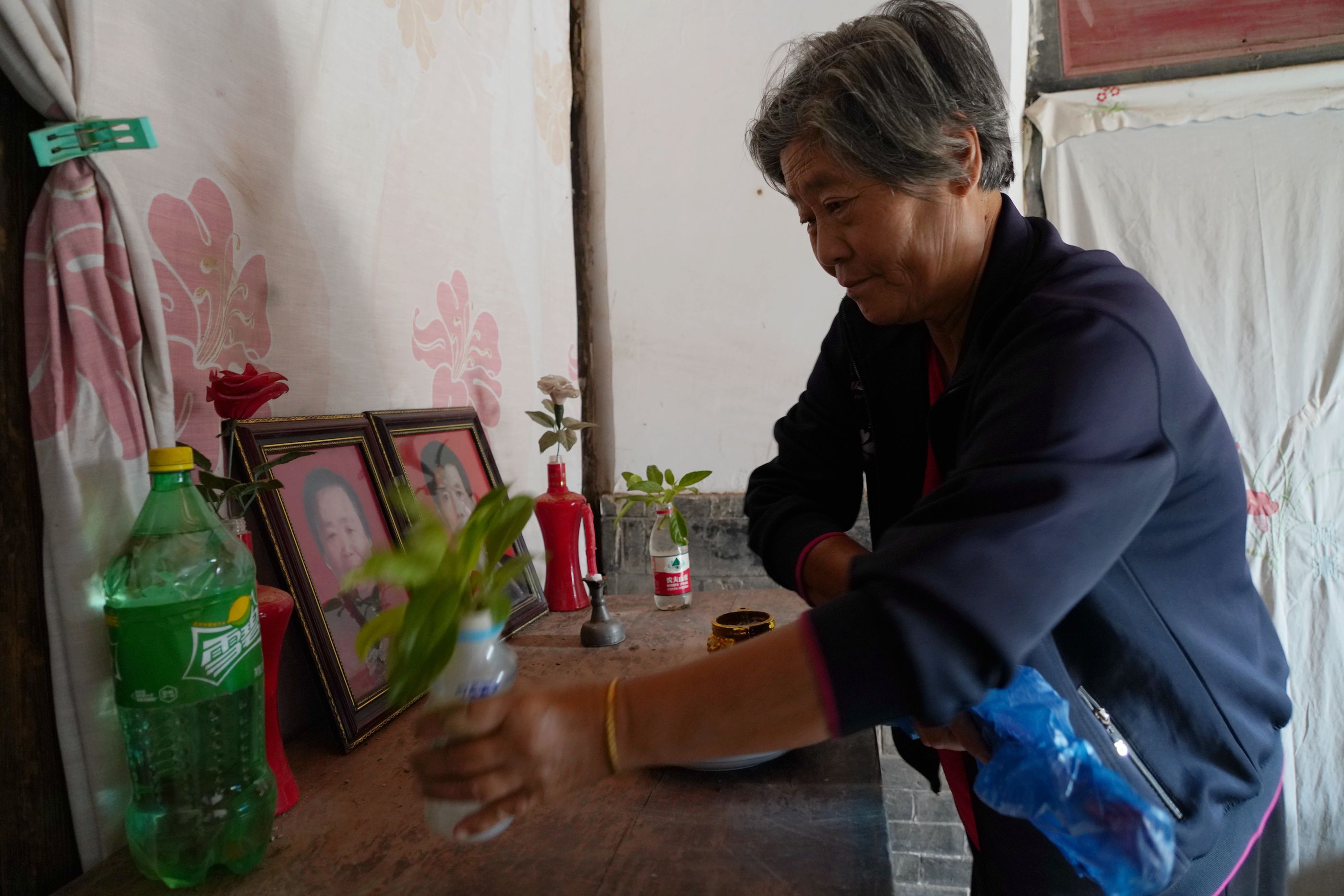 圖為張大媽在整理哥嫂遺像