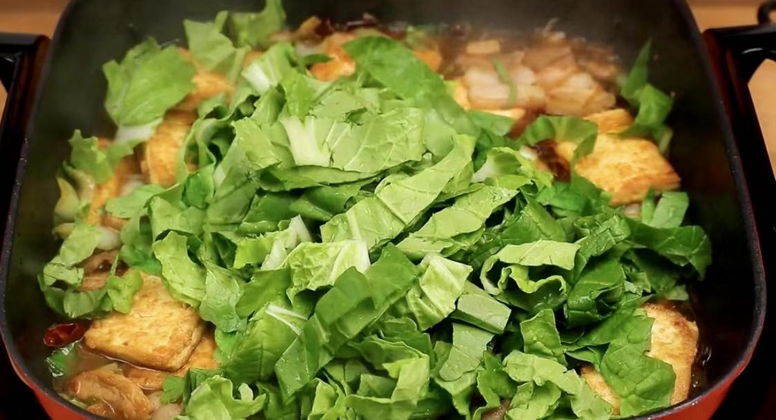 下入菜叶子 9,等白菜梗炖至软烂,豆腐入味后,加入适量提前洗好切段的