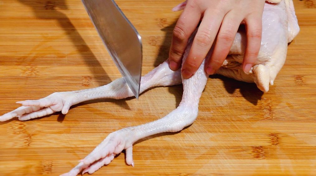 选用不超过2斤的仔鸡,用刀先剁去鸡脚,鸡头和鸡翘(鸡屁股).