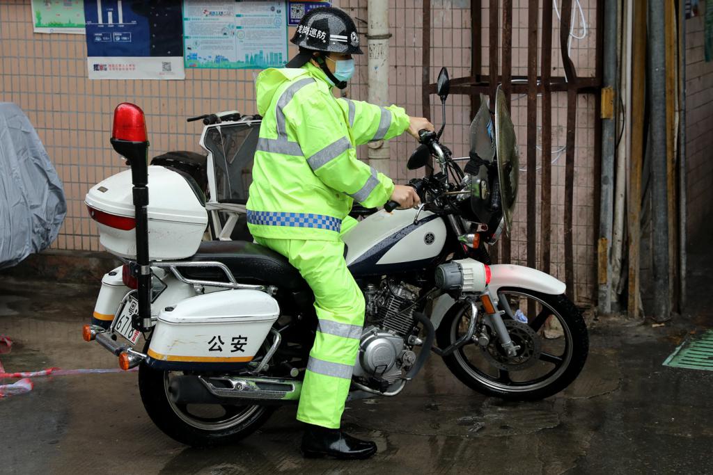 治安协管员冒雨骑着摩托车在社区内巡逻.
