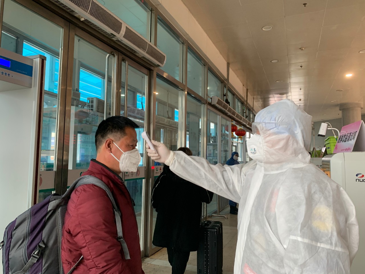 在淄博火车站,青年志愿者"全副武装"给旅客检测体温.