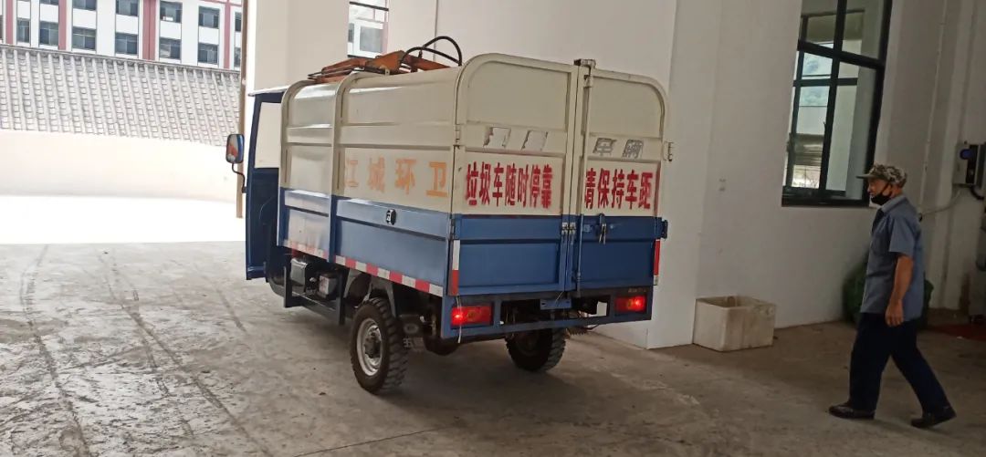 垃圾中转站里,一辆辆装满垃圾车辆正在进出,将垃圾倒在压缩箱中,按下