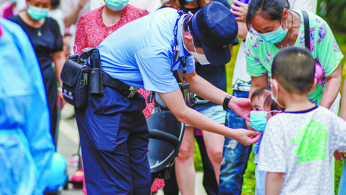 9月2日，四川省成都市公安局新都区分局大丰北派出所辅警帮助小朋友戴好口罩。陈美屹 摄